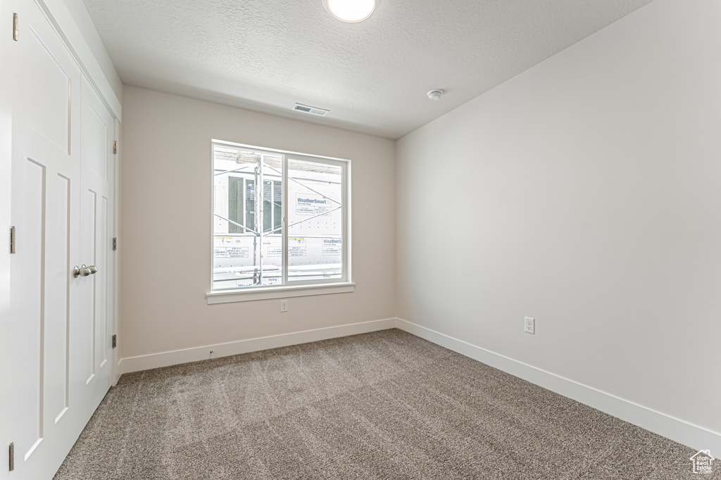 Unfurnished bedroom featuring a textured ceiling and carpet flooring