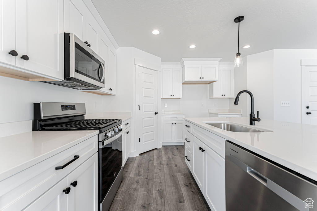 Kitchen with appliances with stainless steel finishes, recessed lighting, dark wood-style flooring, white cabinetry, and pendant lighting