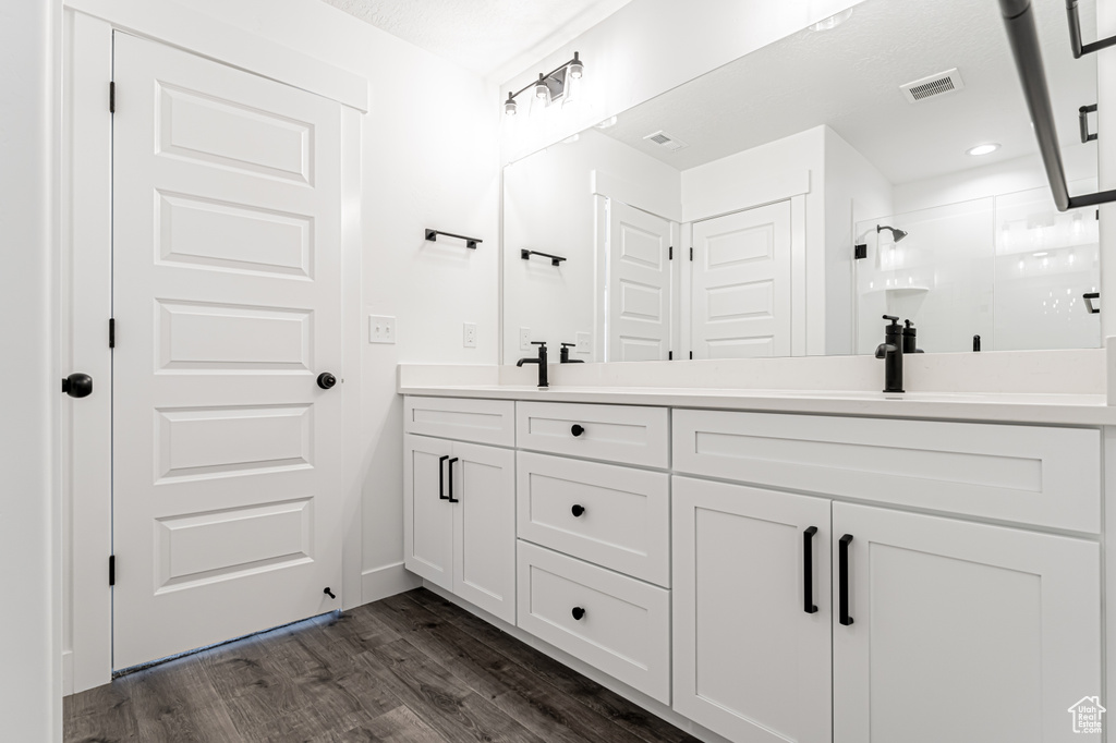 Bathroom featuring double vanity, a shower stall, wood finished floors, and recessed lighting