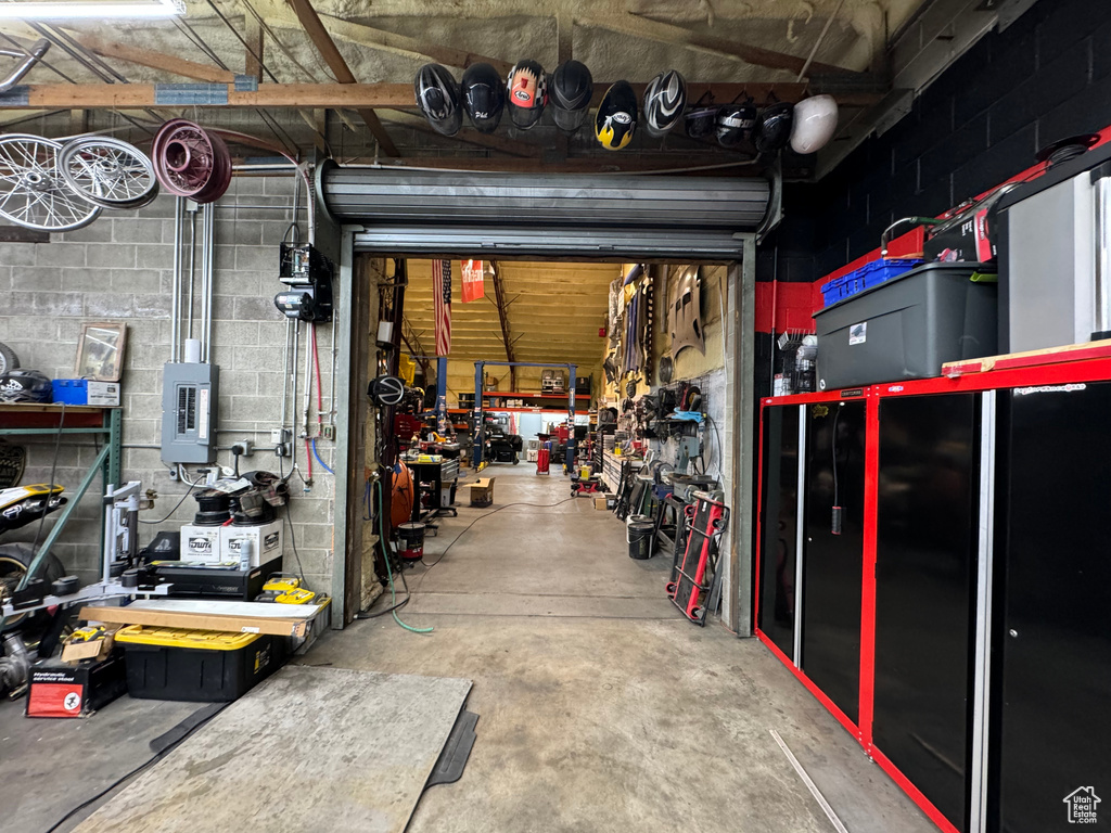 Garage featuring electric panel, a workshop area, and concrete block wall