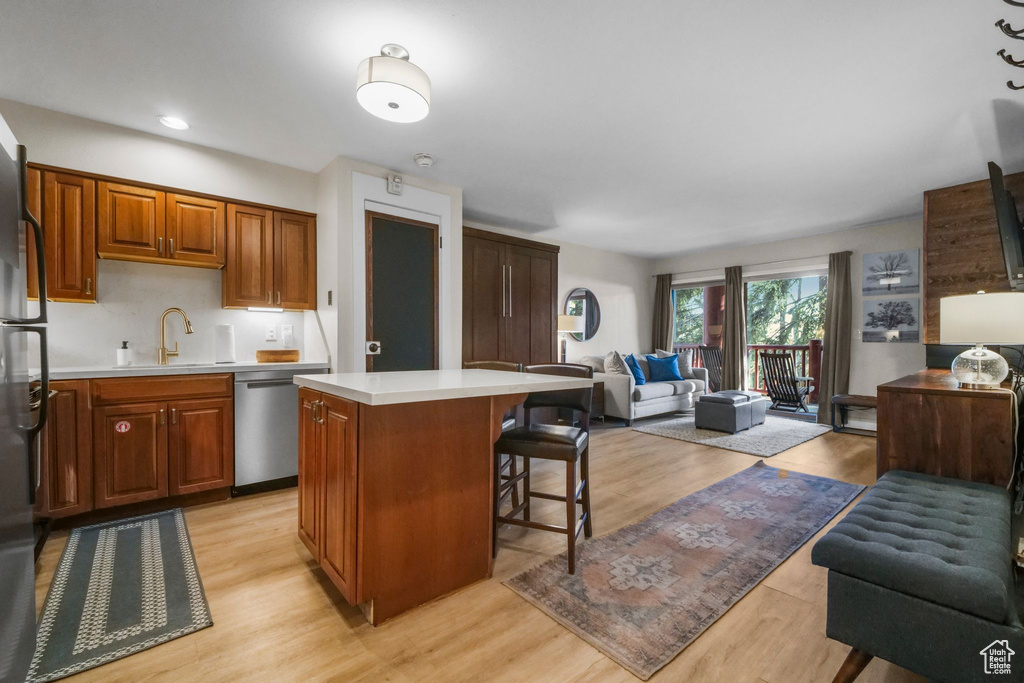 Kitchen with a kitchen bar, a sink, open floor plan, light countertops, and dishwasher