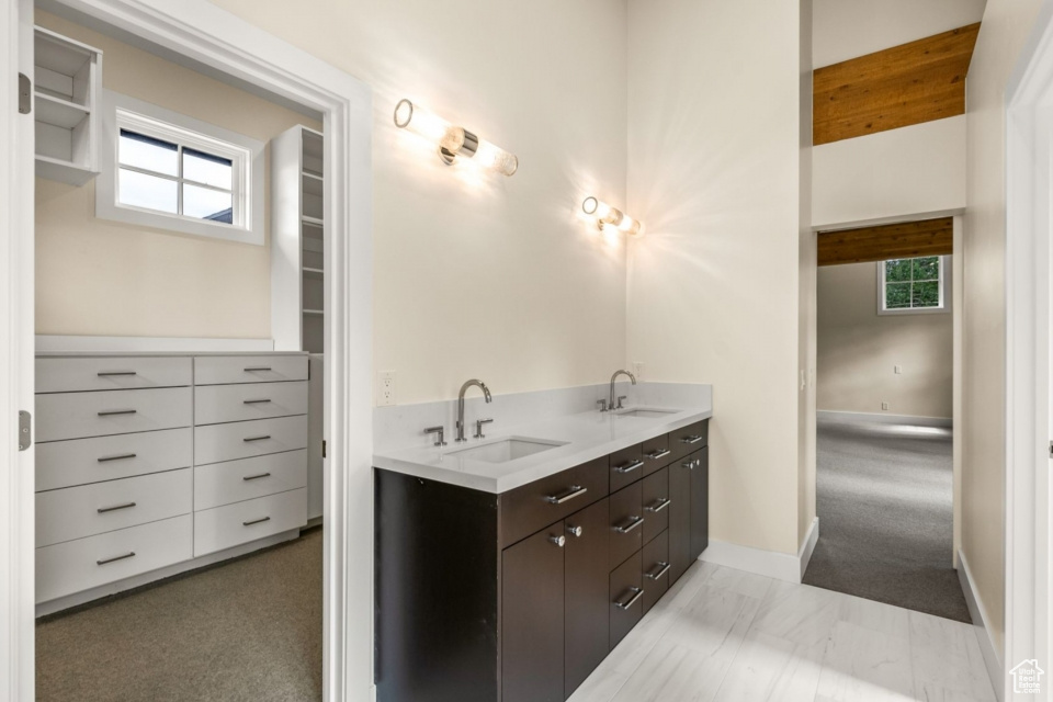 Full bathroom featuring double vanity, a healthy amount of sunlight, and a sink