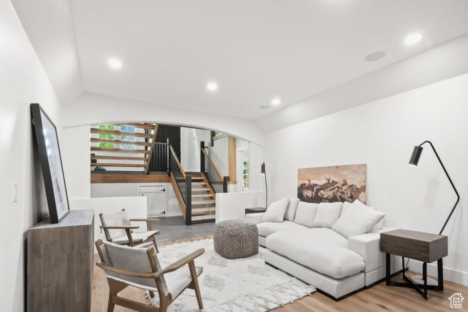 Living room with stairway, wood finished floors, lofted ceiling, recessed lighting, and arched walkways