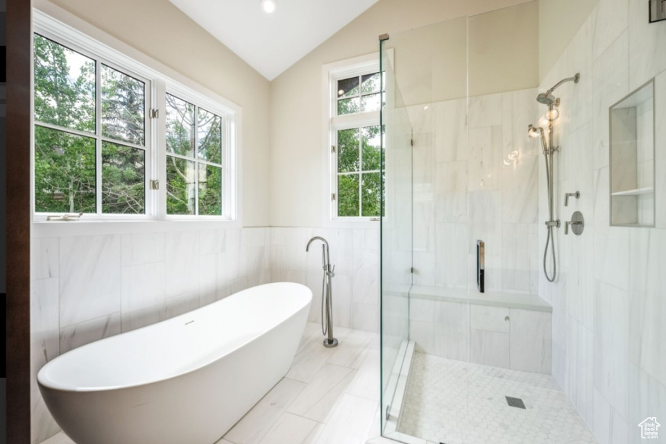 Bathroom featuring lofted ceiling, a freestanding bath, and a stall shower