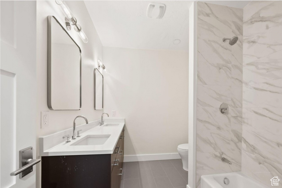 Bathroom with double vanity, toilet, baseboards, and a sink