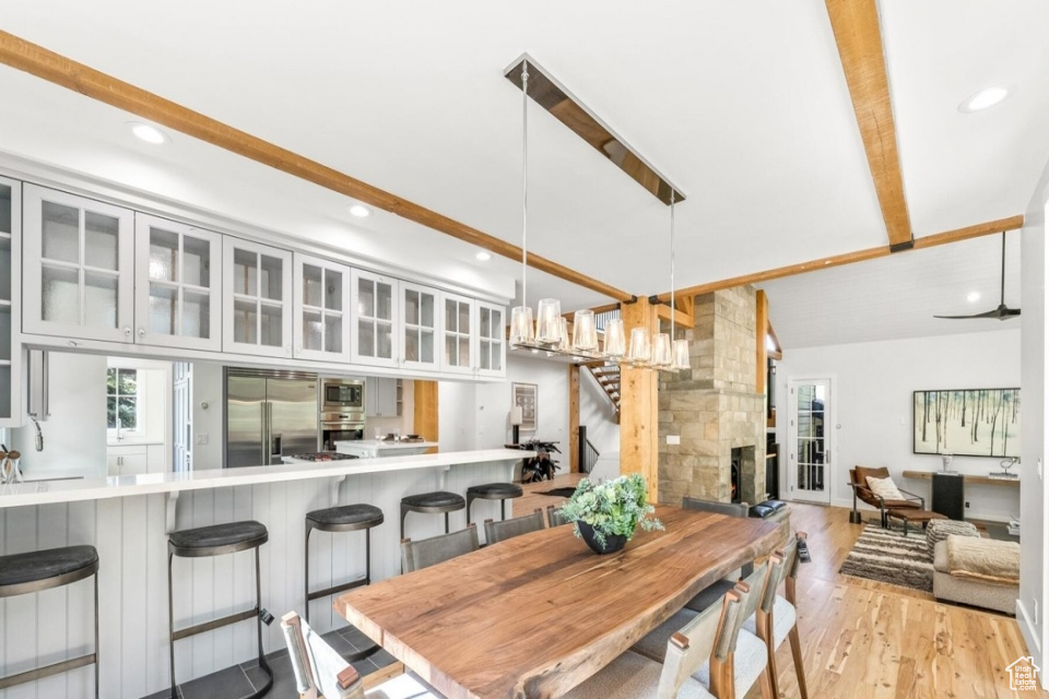 Dining room featuring stairs, light wood-style flooring, vaulted ceiling with beams, and recessed lighting