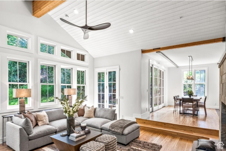 Sunroom / solarium with a ceiling fan and vaulted ceiling with beams
