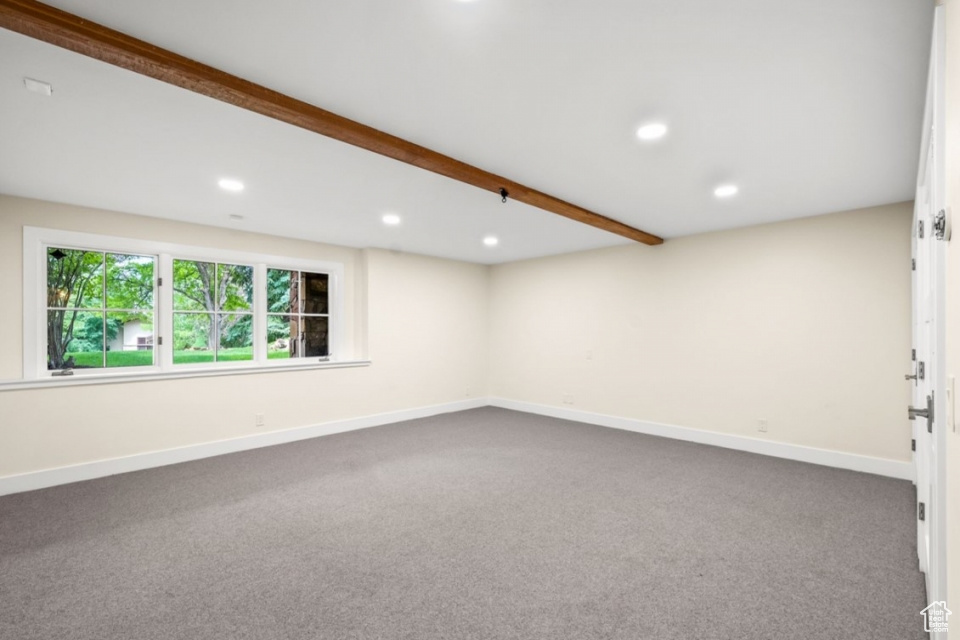 Empty room with beamed ceiling, recessed lighting, baseboards, and dark colored carpet