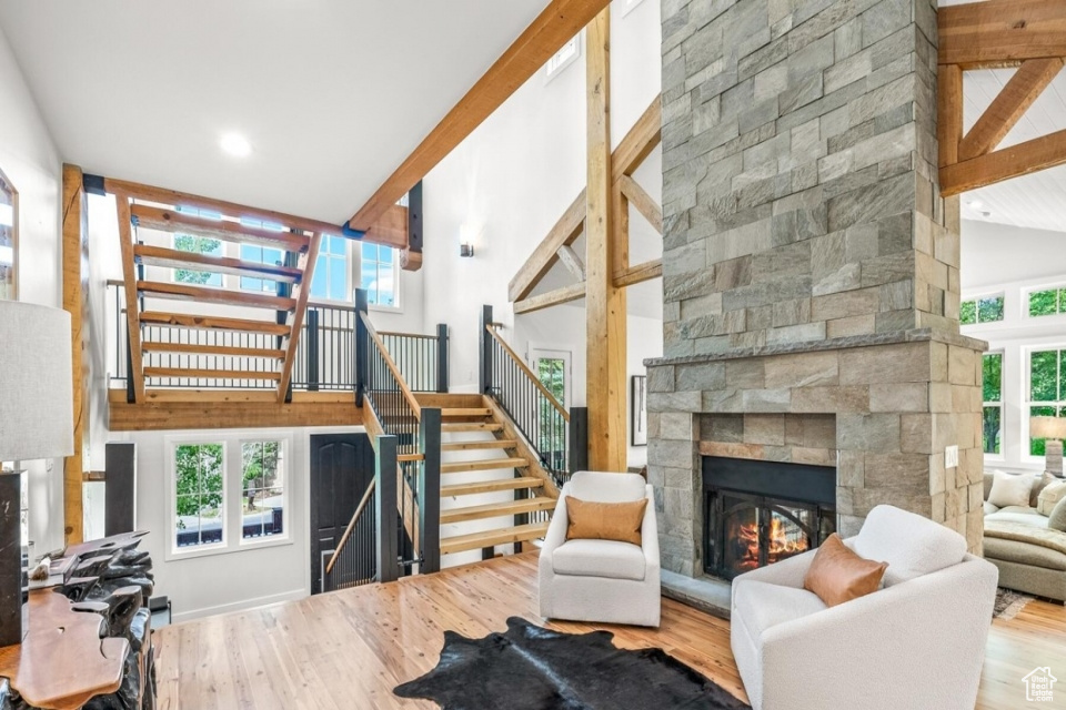 Living area featuring a stone fireplace, high vaulted ceiling, and wood finished floors