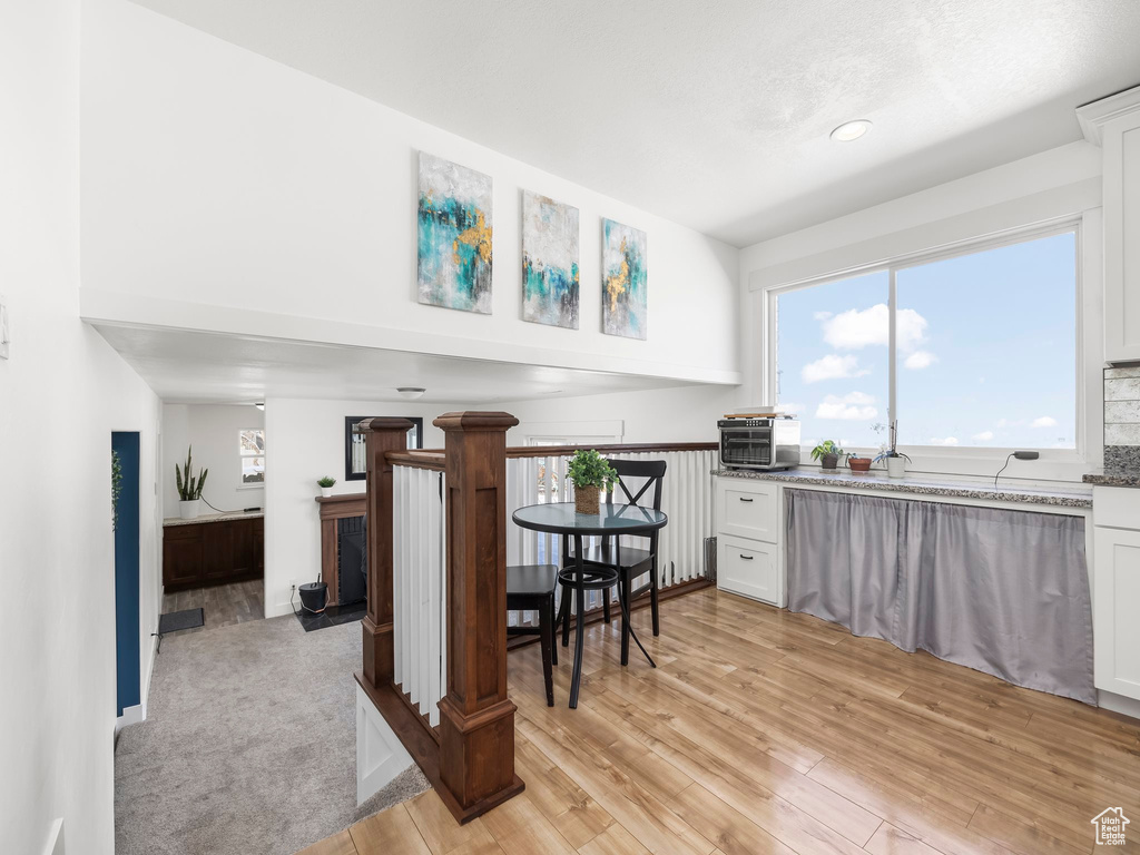 Kitchen featuring white cabinets, light wood-type flooring, and stone counters