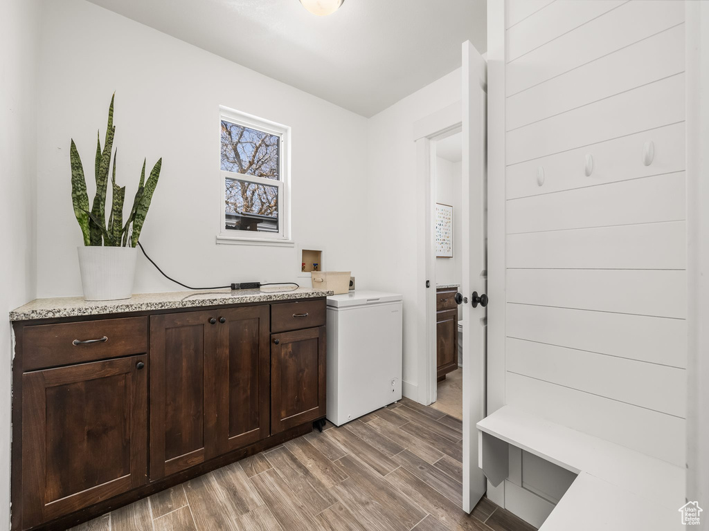 Laundry area featuring hookup for a washing machine, cabinet space, and wood finish floors