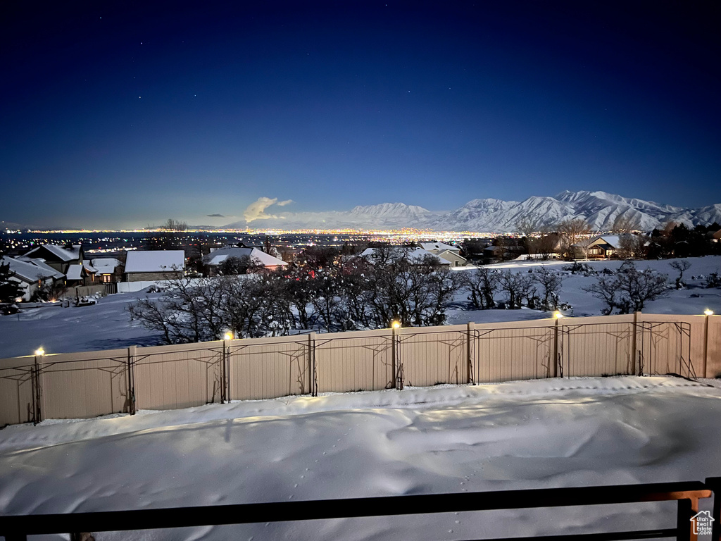 Yard covered in snow with a mountain view and fence