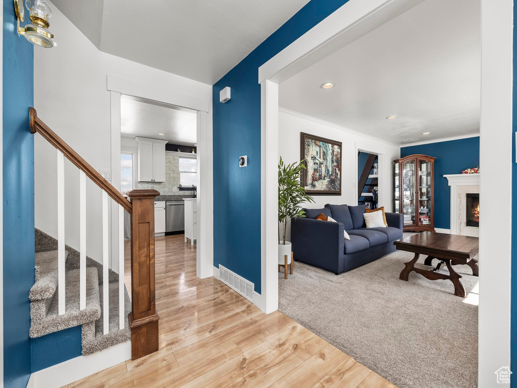 Living area with stairs, light wood-style flooring, plenty of natural light, and a premium fireplace