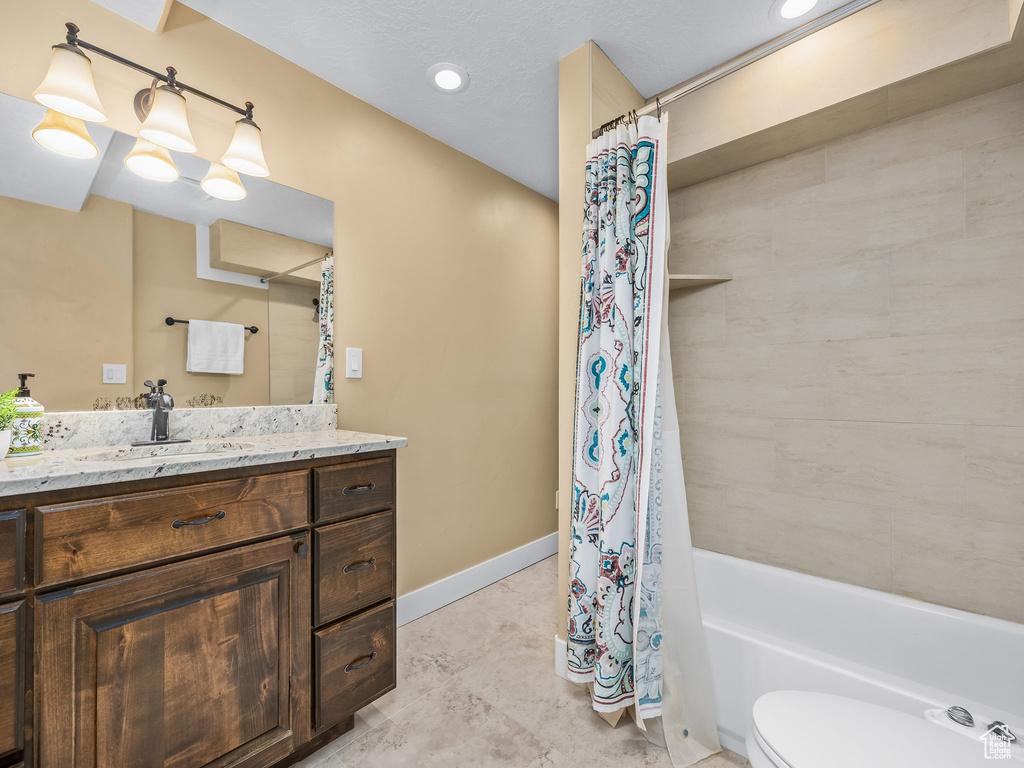 Full bath with vanity, shower / bath combo with shower curtain, toilet, and baseboards