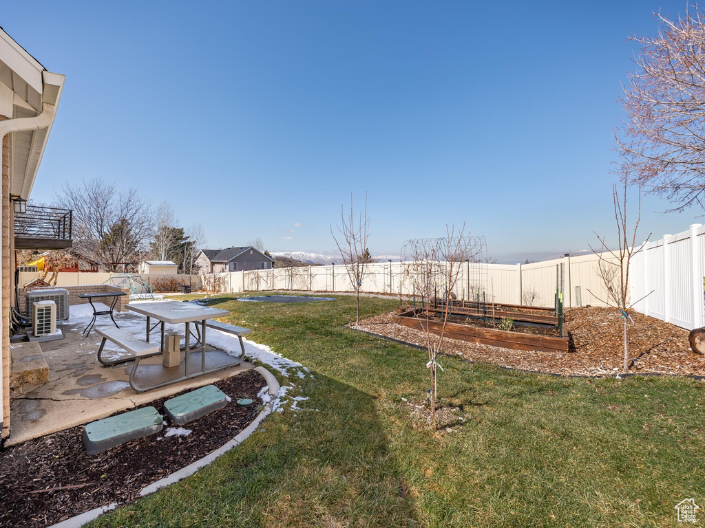 View of yard with central AC unit, a garden, a patio area, and a fenced backyard