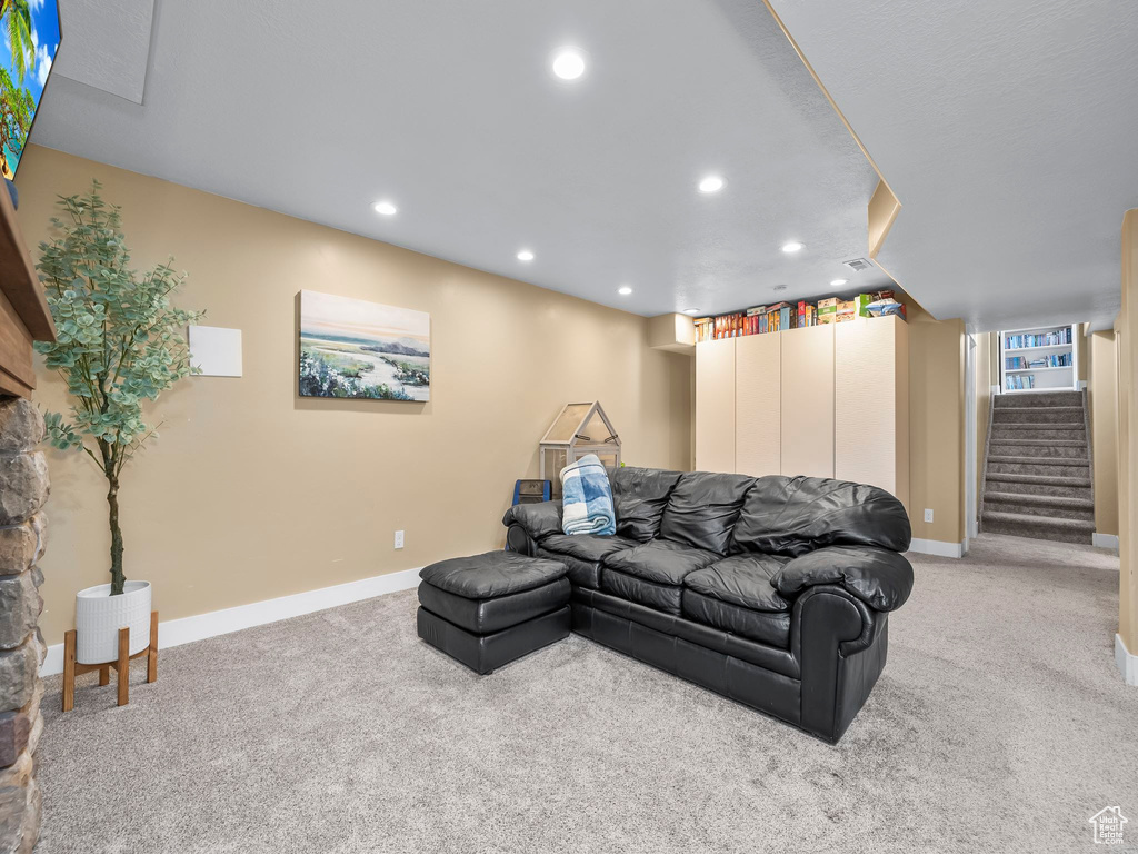 Living area featuring recessed lighting, light colored carpet, stairs, and baseboards