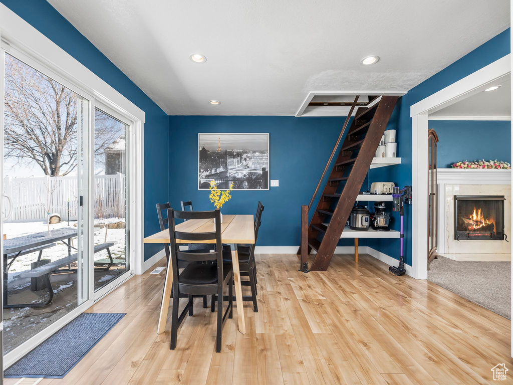 Dining room featuring a high end fireplace, baseboards, stairway, recessed lighting, and wood finished floors