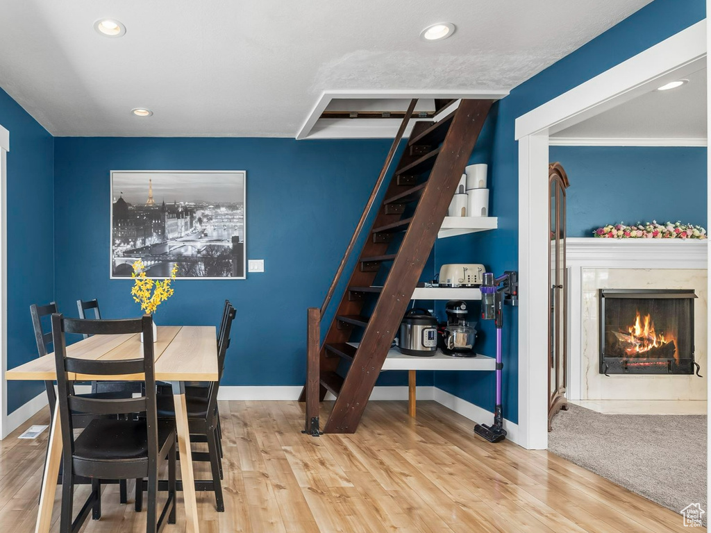 Dining room featuring stairway, wood finished floors, baseboards, recessed lighting, and a high end fireplace