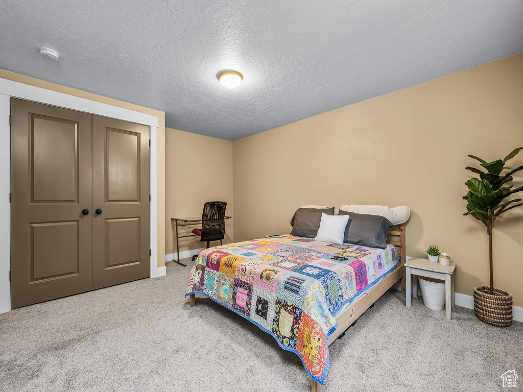 Bedroom featuring baseboards, carpet, and a textured ceiling