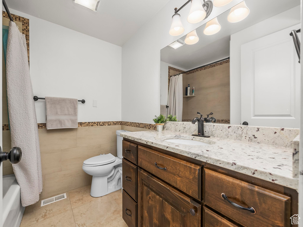 Bathroom featuring vanity, visible vents, wainscoting, tile walls, and toilet