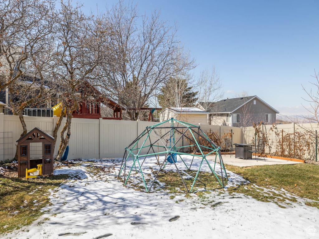 Yard layered in snow featuring a patio and a fenced backyard