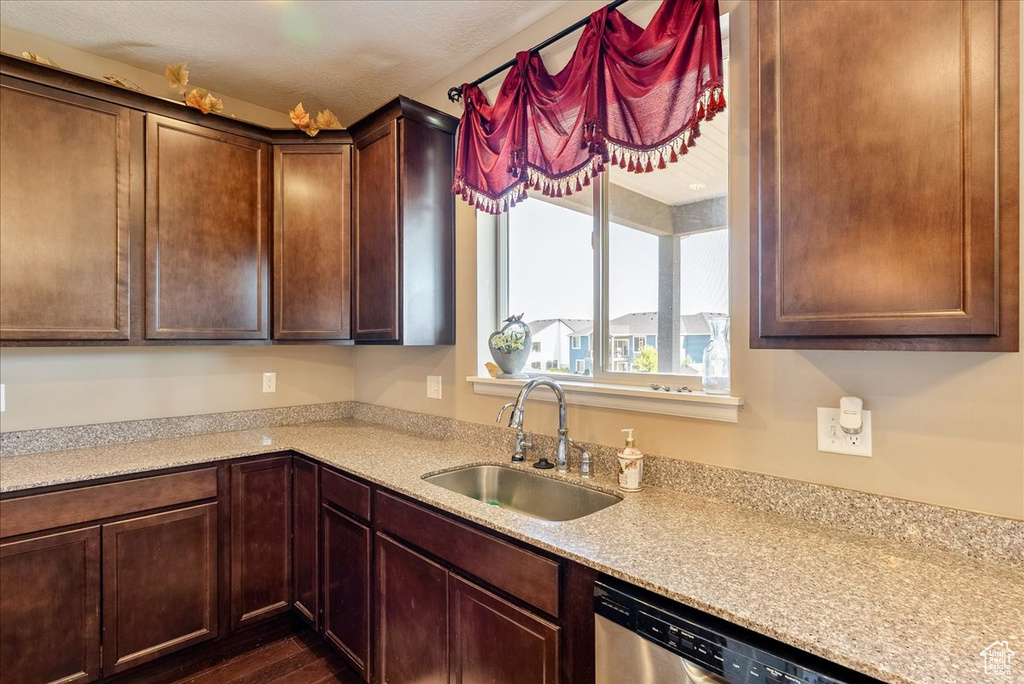 Kitchen with a sink, dishwasher, light countertops, and dark wood finished floors