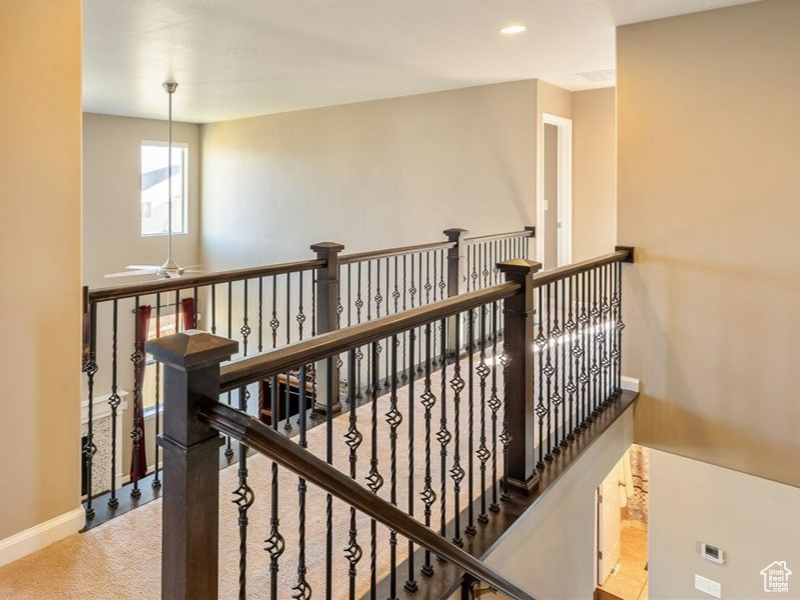 Corridor with light colored carpet, an upstairs landing, plenty of natural light, and recessed lighting