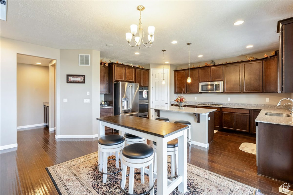 Kitchen featuring appliances with stainless steel finishes, a kitchen island, a sink, dark wood-style floors, and recessed lighting