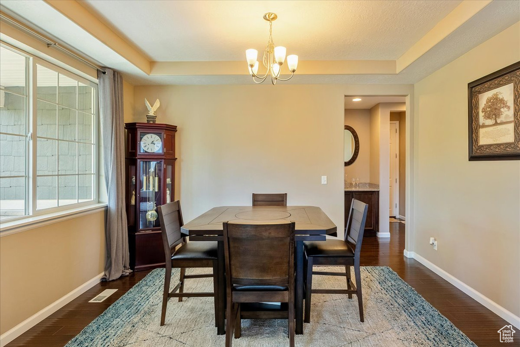 Dining area with a chandelier, baseboards, healthy amount of natural light, and wood finished floors