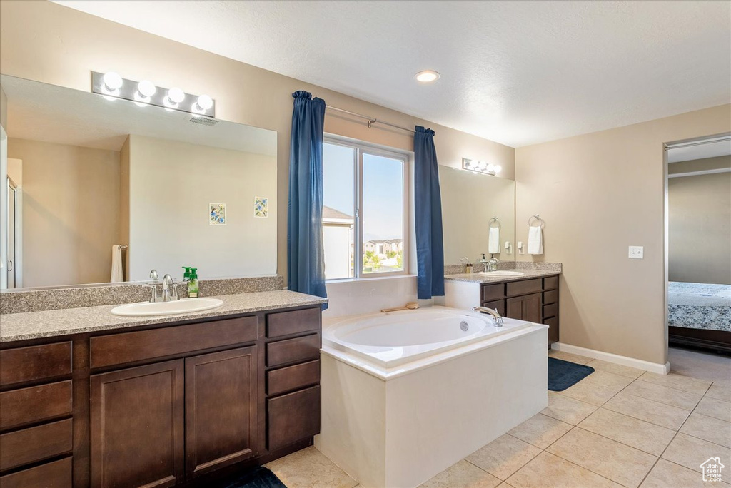 Ensuite bathroom featuring a bath, two vanities, and tile patterned flooring