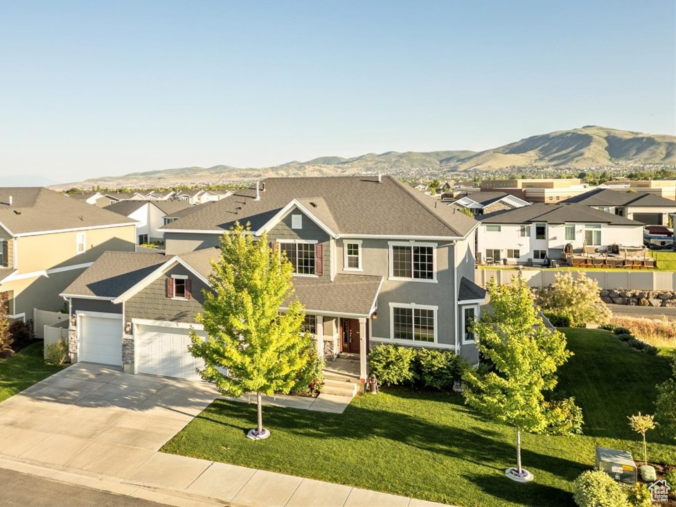 Traditional-style house featuring a residential view, a mountain view, concrete driveway, a front lawn, and a garage