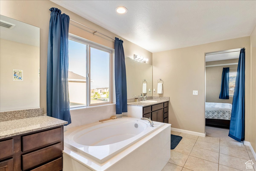 Ensuite bathroom featuring vanity, a garden tub, baseboards, and tile patterned flooring