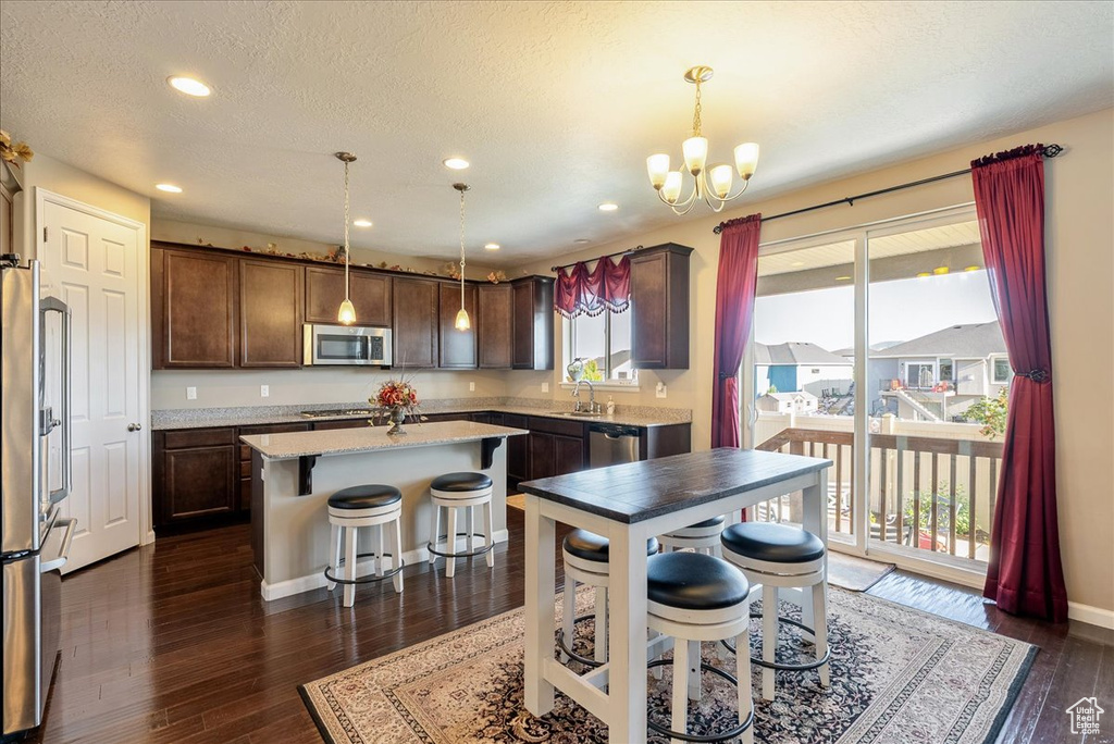 Kitchen with appliances with stainless steel finishes, a sink, a center island, a chandelier, and a kitchen breakfast bar