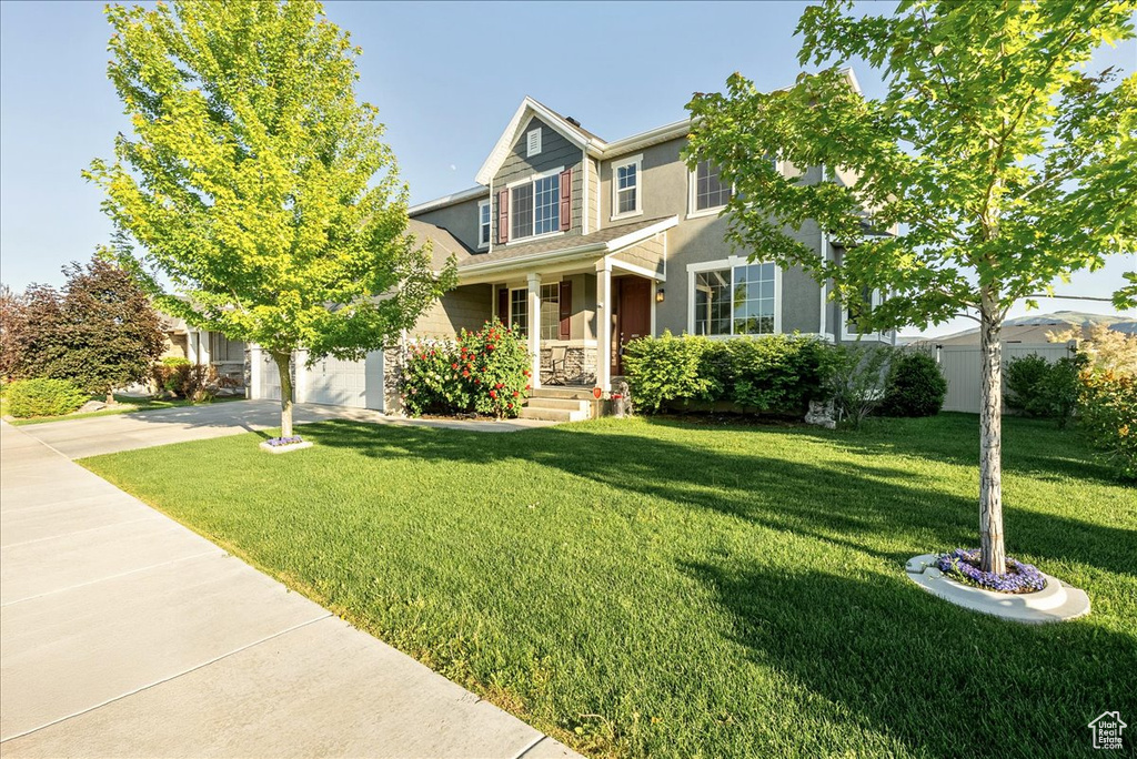 View of front facade featuring concrete driveway, a garage, a front yard, and stucco siding