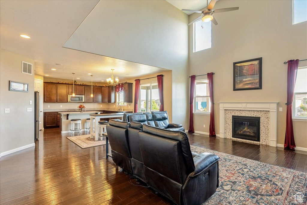 Living area with a chandelier, dark wood-type flooring, ceiling fan, plenty of natural light, and recessed lighting