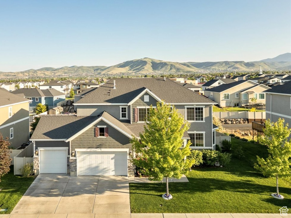 View of front of home with a residential view, concrete driveway, and a mountain view