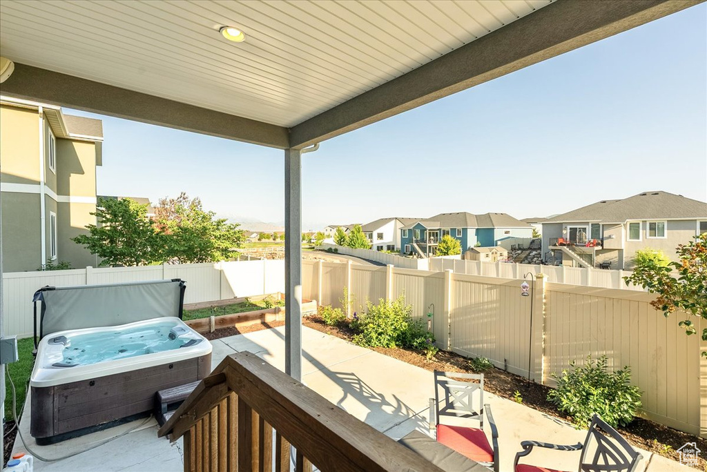 Fenced backyard featuring a hot tub, a residential view, and a patio