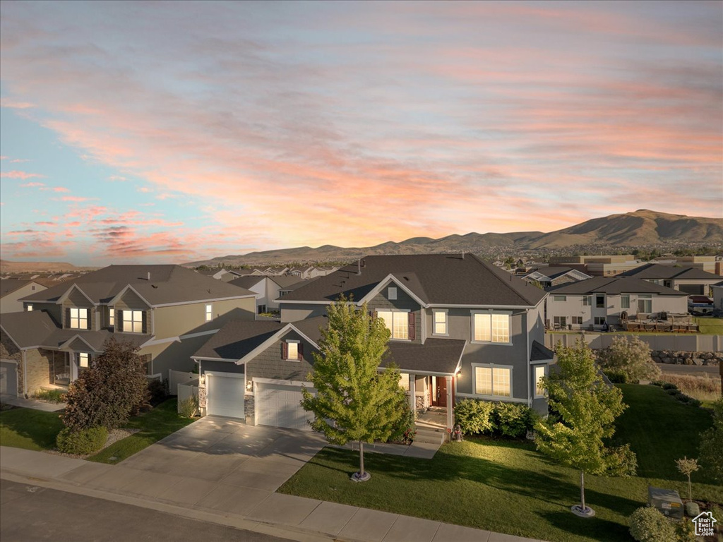 Traditional-style house featuring concrete driveway, a residential view, a mountain view, a yard, and a garage
