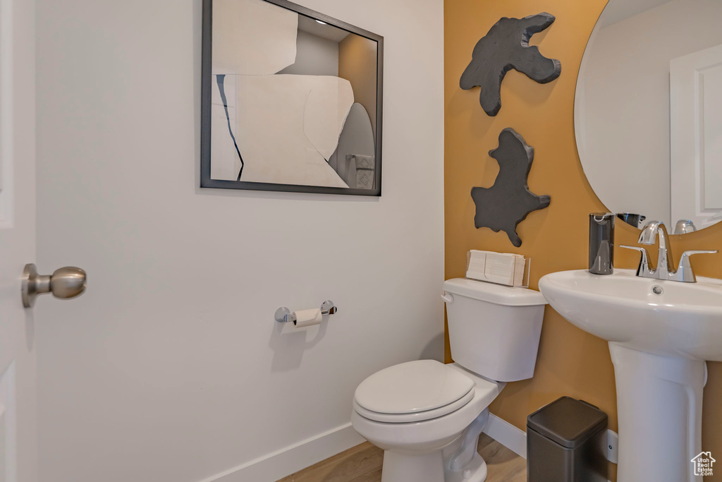 Bathroom featuring baseboards, a sink, toilet, and wood finished floors