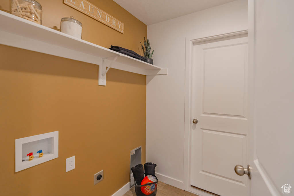 Washroom featuring hookup for a washing machine, hookup for an electric dryer, laundry area, baseboards, and light wood finished floors