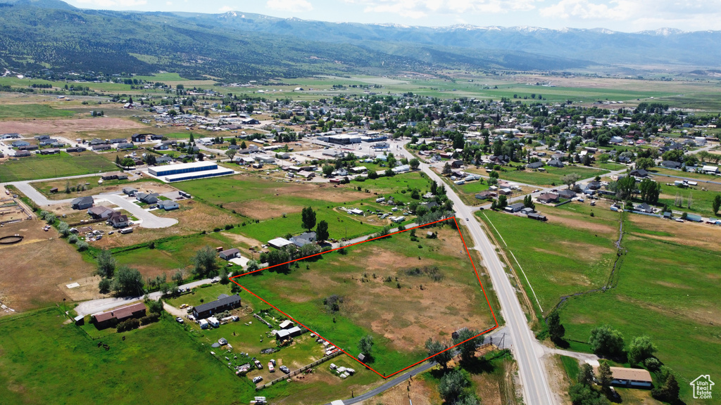 Aerial view of property and surrounding area with property parcel outlined and a mountainous background