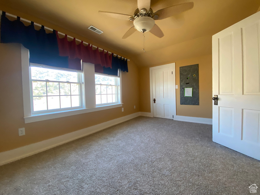 Carpeted empty room featuring a ceiling fan, baseboards, and visible vents