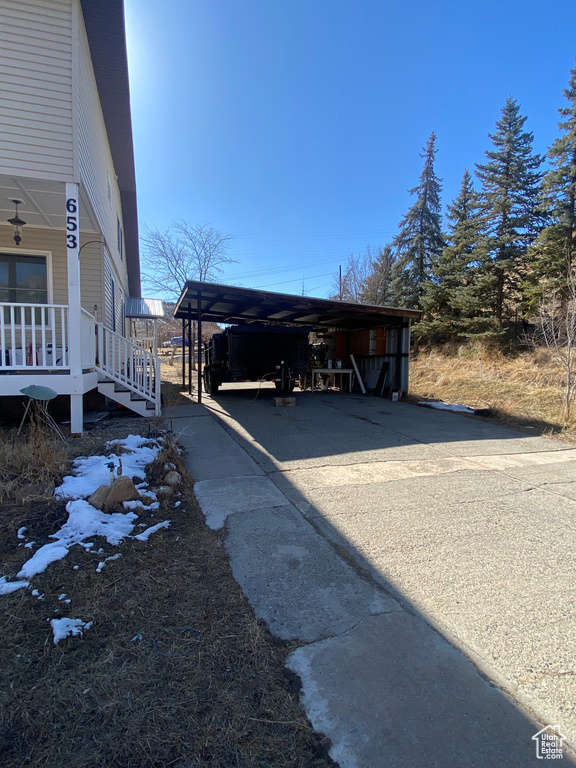 View of side of home featuring a carport, a porch, and driveway