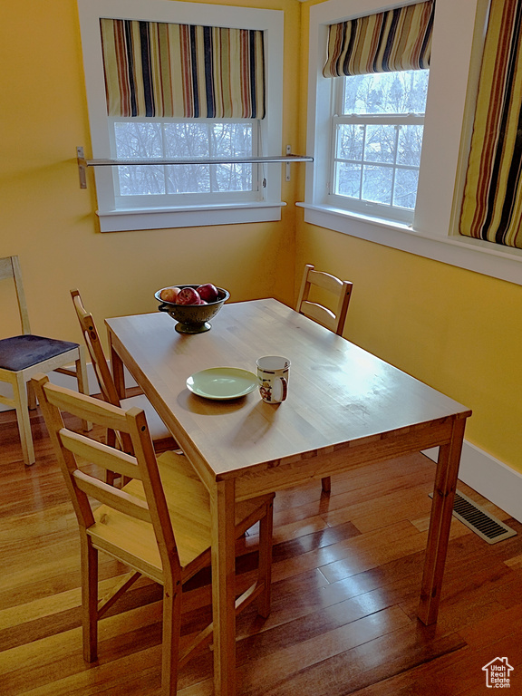 Dining space with visible vents, baseboards, and wood finished floors