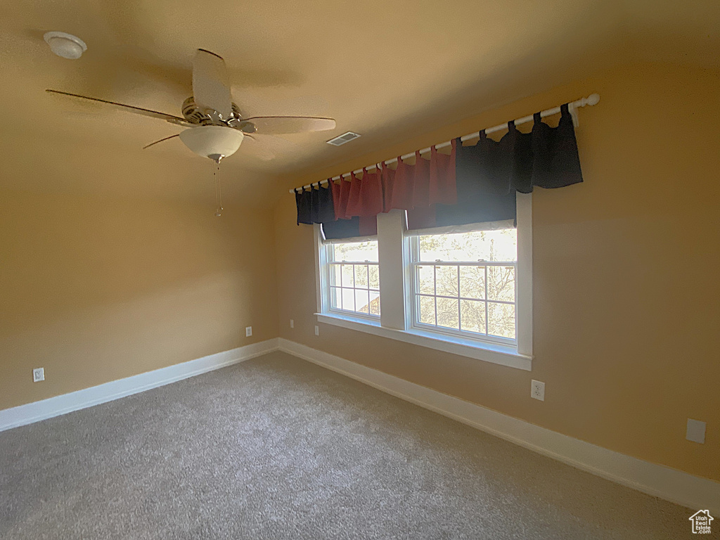 Spare room with carpet, visible vents, baseboards, and ceiling fan