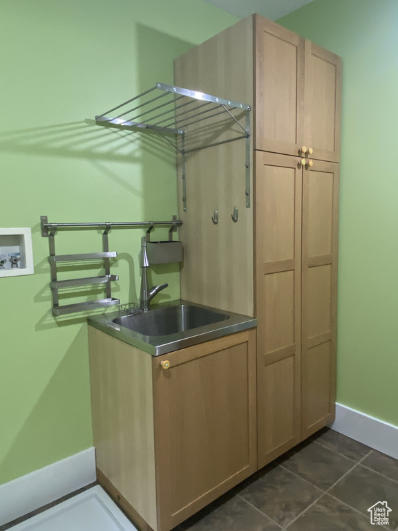 Clothes washing area featuring washer hookup, dark tile patterned floors, a sink, cabinet space, and baseboards