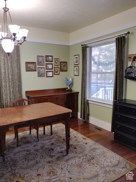 Dining space featuring a notable chandelier, wood finished floors, visible vents, and baseboards