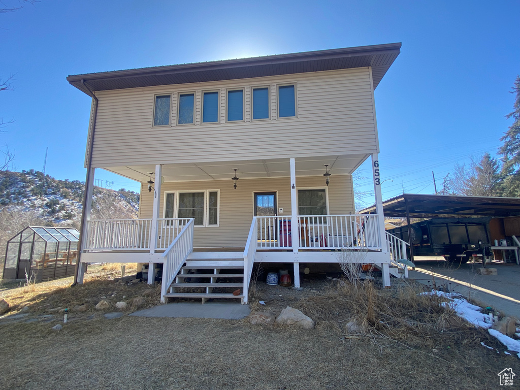 View of front of home featuring a greenhouse, a porch, and an outdoor structure