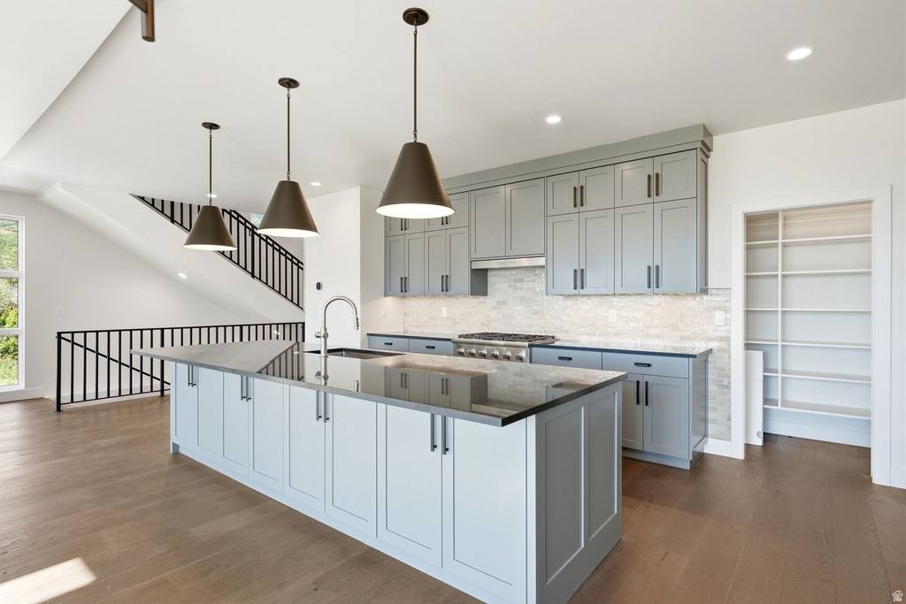 Spacious kitchen featuring a large island with sink, ample cabinetry, stainless steel appliances, and wood-finish flooring