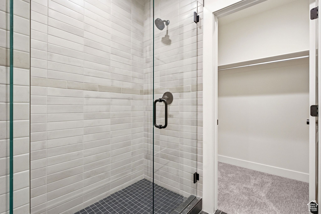 Glass-enclosed shower featuring white subway tile walls with a contrasting accent band, dark mosaic floor tiling, and matte black fixtures